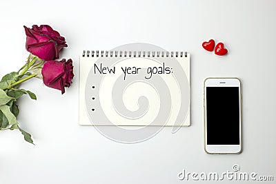 New yearâ€™ s goals words on notebook with roses and smart phone Stock Photo